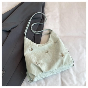 Detail of mint green textured handbag featuring metallic butterfly and silver hardware