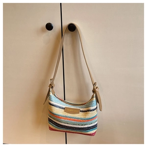 Close-up of a colorful woven rainbow shoulder bag featuring a leather fashion label tag
