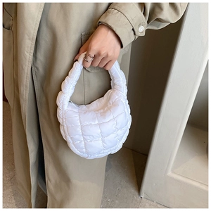 Detailed view of white quilted puff tote bag featuring textured fabric and silver zipper