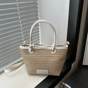 Détail de la texture tissée et de l'anse en cuir blanc du sac cabas en paille