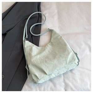 Detail view of mint green pleated tote bag with silver hardware and adjustable strap