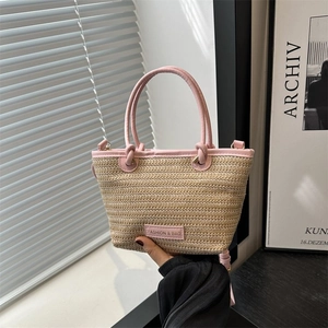 Détail du sac cabas en paille tissée avec poignée en cuir rose et étiquette de mode