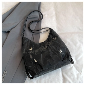 Detailed shot of a black pleated shoulder bag featuring four silver butterfly metal charms
