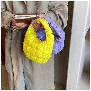 Close-up of bright yellow and lavender quilted puffer mini handbags on a model