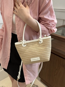Détail du sac cabas en paille tissée avec garniture en similicuir blanc et étiquette