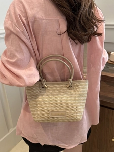 Détail du sac cabas en paille tressée avec bordure en cuir marron et bandoulière amovible