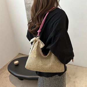 Fashionable woven straw shoulder bag with pink rope straps and cream lace bow detail