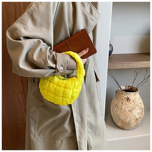 Detailed close-up of bright yellow quilted cloud bag with crescent design and shiny finish