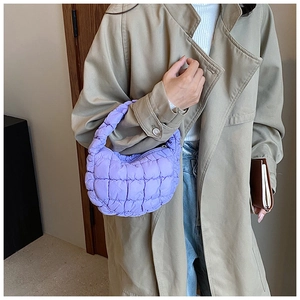 Close-up of a purple quilted puff mini bag held by a model in a stylish trench coat
