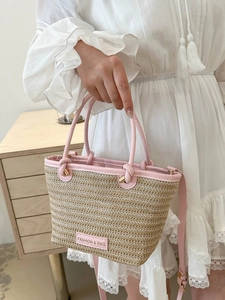 Détail du sac cabas en paille tissée avec garniture en cuir rose et étiquette mode