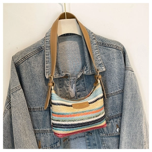 Detail of woven rainbow texture on shoulder bag with brown leather strap and logo