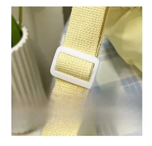 Detail of adjustable lemon yellow canvas shoulder strap with white plastic buckle