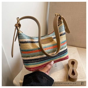 Detail of colorful woven shoulder bag with brown leather strap and golden logo plate