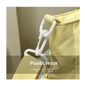Close-up of yellow fabric bag featuring a white plastic swivel hook and woven strap