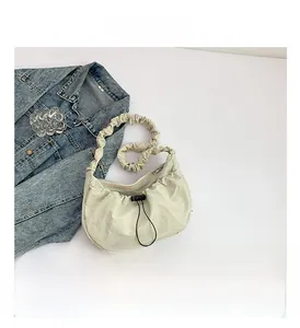 Close-up of beige nylon cloud bag showing pleated strap details and drawstring closure