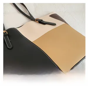 Detail of color-block tote bag featuring white contrast stitching and golden metal buckle