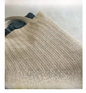 Détail du sac cabas en paille tissée avec motif en V et bandoulière en cuir blanc