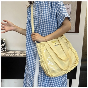 Detail of light yellow canvas tote bag with decorative ruffles and transparent PVC pocket