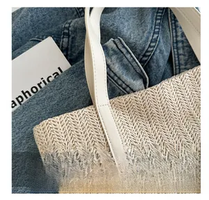 Gros plan du sac en paille beige avec texture en V et bandoulière en cuir blanc