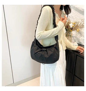 Detail shot of black nylon crossbody bag with drawstring closure and ruched shoulder strap