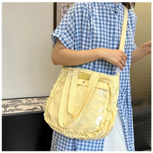 Detail of yellow tote bag featuring side ruffles and a clear PVC display pocket