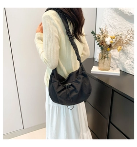 Detail of black nylon shoulder bag featuring stylish drawstring and pleated design