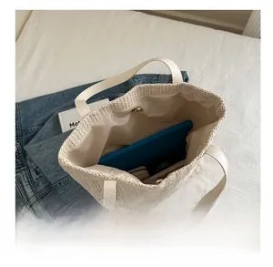 Vue intérieure du grand sac cabas tissé beige montrant sa capacité pour tablettes