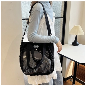 Detail of black tote bag featuring a transparent PVC window and adjustable shoulder strap