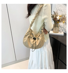 Lifestyle view of a khaki drawstring nylon tote bag with scrunchie style shoulder strap