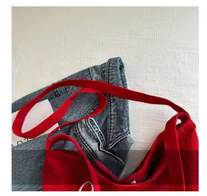 Detail view of red corduroy tote bag showing wide shoulder strap and magnetic closure