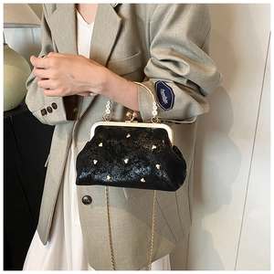 Detail of black glossy kiss-lock clutch with gold heart studs and metal chain strap