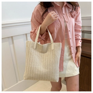 Détail latéral d'un sac cabas en paille tissée avec texture ondulée et anses en cuir synthétique
