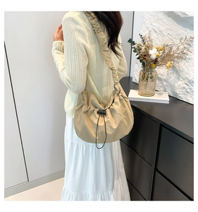 Detail view of the drawstring closure and ruched shoulder strap on a khaki nylon tote bag