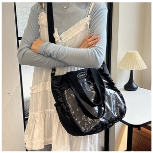 Detail of black tote bag with clear window panel and decorative ruffled edges for style