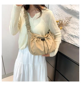 Detail of khaki nylon tote bag featuring drawstring closure and ruffled shoulder strap