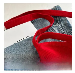Detail shot of a red corduroy tote bag showing soft textured fabric and logo stitching
