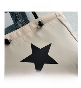 Close-up of cream quilted tote bag showing black star print and metal drawstring hardware