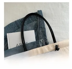 Detail of soft beige quilted tote bag with black tubular handles and metal eyelets