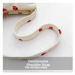 Détail du sac en velours côtelé à motif fraises avec fermeture éclair dorée et bandoulière