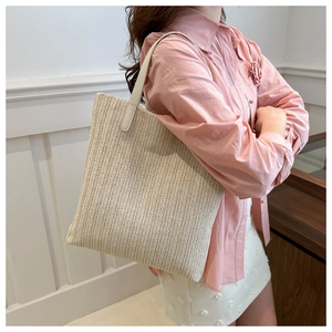 Détail du sac cabas tressé crème montrant la texture diagonale et la bandoulière en cuir