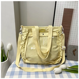 Close-up of light yellow tote bag with clear PVC pocket and elegant ruffle details