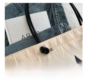 Detail view of beige tote bag featuring a large black star pattern and drawstring closure