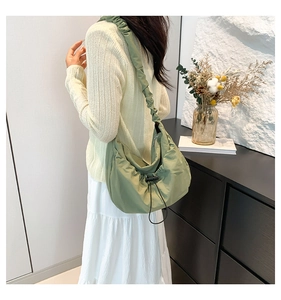 Detail of light green nylon shoulder bag featuring elegant pleated texture and drawstring