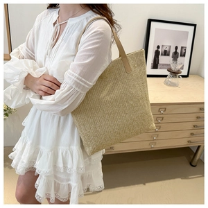 Détail d'un sac cabas tissé beige avec des anses en similicuir marron clair et texture fine