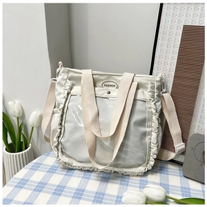 Detailed view of the wavy pleated edge and transparent front pocket of the cream tote bag