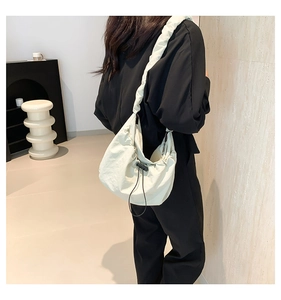Detailed side view of beige nylon tote bag with ruched strap on a female model