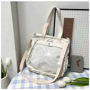 Detail of a creamy white ruffled tote bag with a clear PVC window for badge display