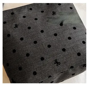 Detailed view of grey chevron fabric featuring black flocked polka dots and embroidered bows