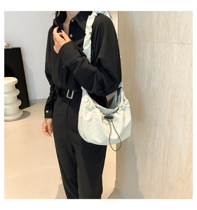 Detail of light green drawstring tote bag with pleated texture and wide shoulder strap