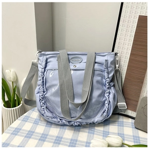 Detail of light blue nylon tote bag showing ruffled edges and grey adjustable strap